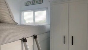 A room with a window, a white wardrobe, and a ladder leaning against the wall.