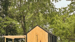 Een houten hut met een veranda, een klein terras en een groot raam.