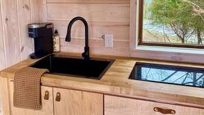 Een houten interieur met een keukenhoek, inclusief een gootsteen, kraan en kastjes.