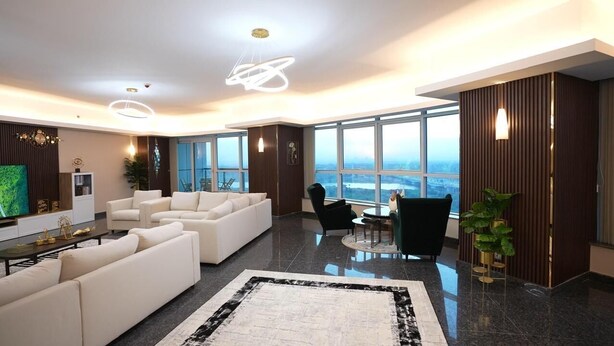 Uma sala de estar moderna com um sofá grande, uma mesa de centro e vista para a cidade.