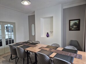A dining area with a long table, cushioned chairs, a mirror, and a framed painting on the wall. - Cosy Spacious Coastal Stay (South Shields)