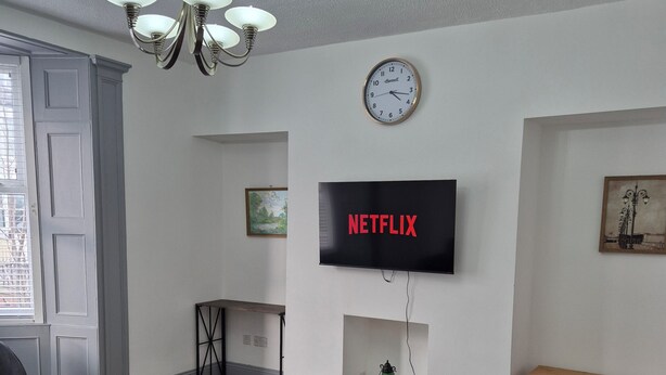 Un salon avec un canapé, une table basse, un téléviseur et une horloge au mur.