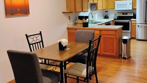 Una cuina compacta amb armaris de fusta, una taula de dinar amb cadires i una petita illa.