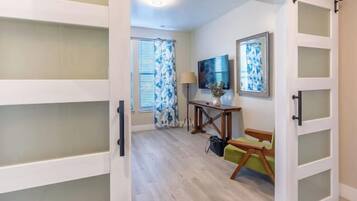 Una habitación con puerta corredera que da a un comedor, una mesa con sillas y una ventana con persianas.