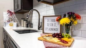 A kitchen counter with a sign, a vase of flowers, and a charcuterie board.