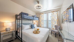 A bunk bed room with a desk, chair, and a bedside table with a lamp. - Main St Suite | King Bed + Loft Bed | Full Kitchen (Pleasant Grove)
