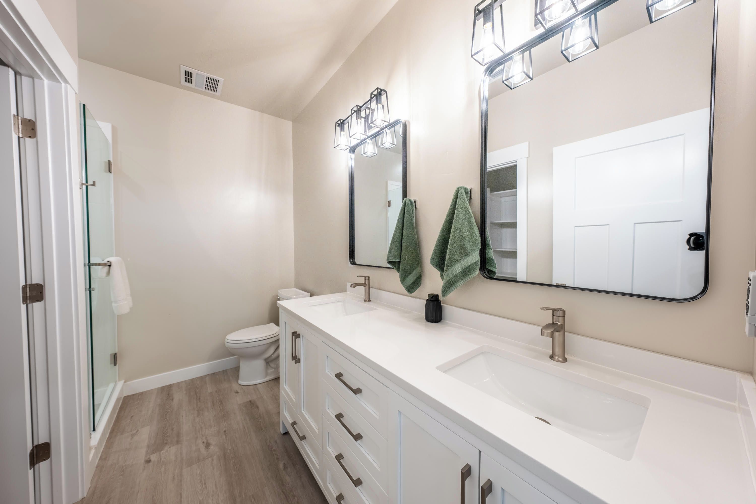 Een moderne badkamer met twee wasbakken, een toilet en een douche.