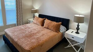 Een slaapkamer met een bed, twee nachtkastjes, een lamp en een raam met gordijnen.