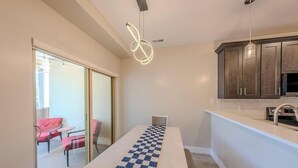 Una cocina moderna con gabinetes oscuros, encimera blanca e iluminación colgante.