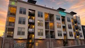 A multi-story building with balconies, a parking lot, and a brick facade.