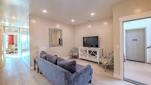 Una sala de estar con un sofá, un televisor, un espejo decorativo y una puerta con el número 403.