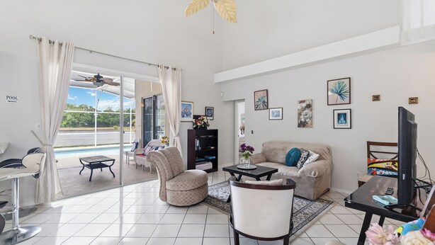 A living room with a sofa, armchairs, a coffee table, a TV, and a pool view. - Spacious 4-bedroom Pool house in charming Kissimmee Close to Disney  with Wi-fi (Kissimmee)