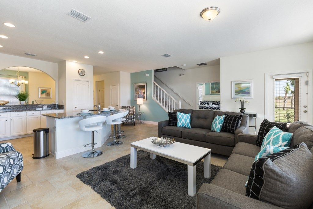 A modern living room with a sofa, coffee table, and kitchen area in the background.