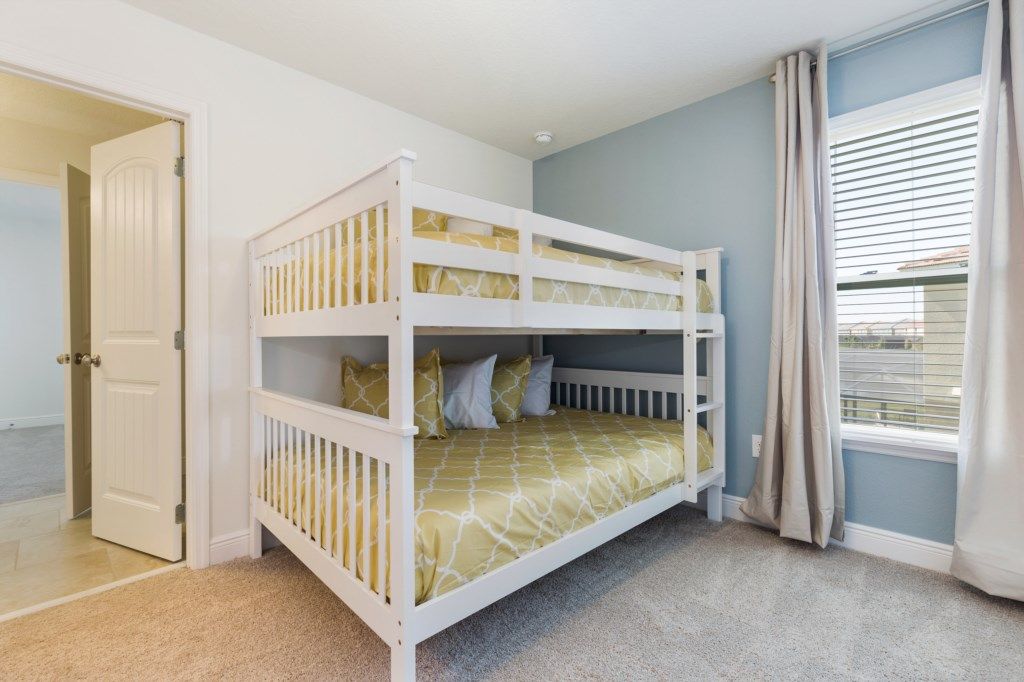 A room with a bunk bed, a door, and a window with blinds.