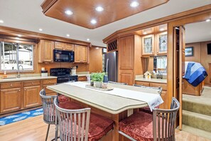 A kitchen with wooden cabinets, a stainless steel refrigerator, a microwave, and a dining table with chairs.
