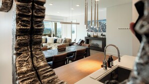 Een moderne keuken met een houten kookeiland, een RVS spoelbak en hangende verlichting.