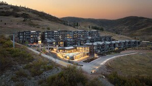 Een modern meerhoog hotel met zwembad, omgeven door glooiend landschap.