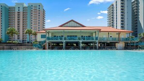 Un hôtel doté d’une grande piscine, d’un espace abrité avec des chaises, et de bâtiments de grande hauteur en arrière-plan.