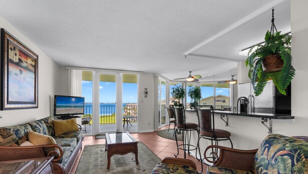 Un salon comprenant un canapé, des fauteuils, une table basse et un téléviseur. Il y a également un balcon avec vue.
