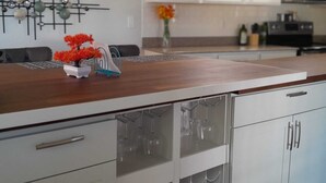 Eine moderne Küche mit weißen Schränken, einer Holz Arbeitsplatte und einem dekorativen Wandelement.