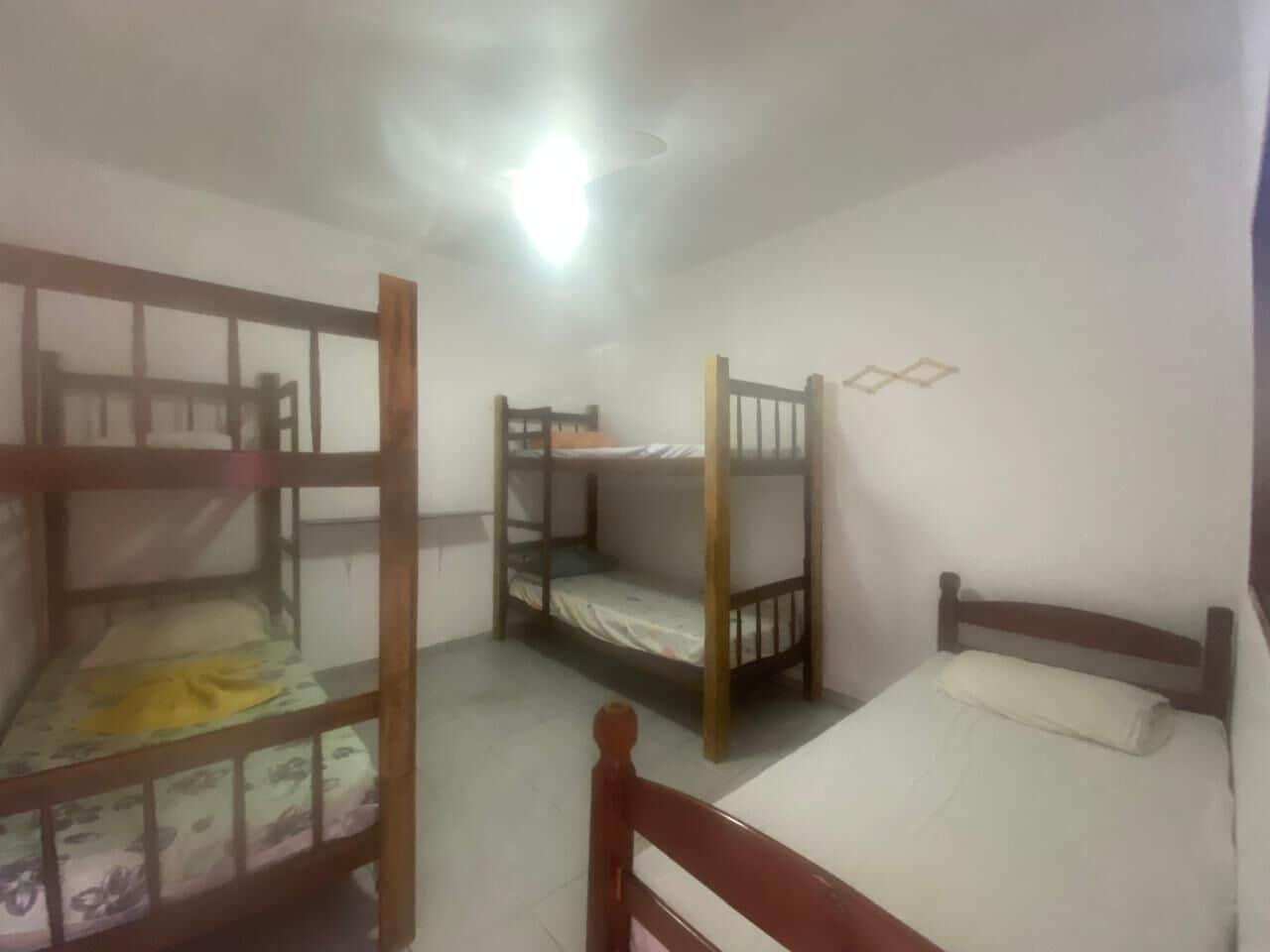 A dormitory room with bunk beds, a ceiling fan, and a single bed.