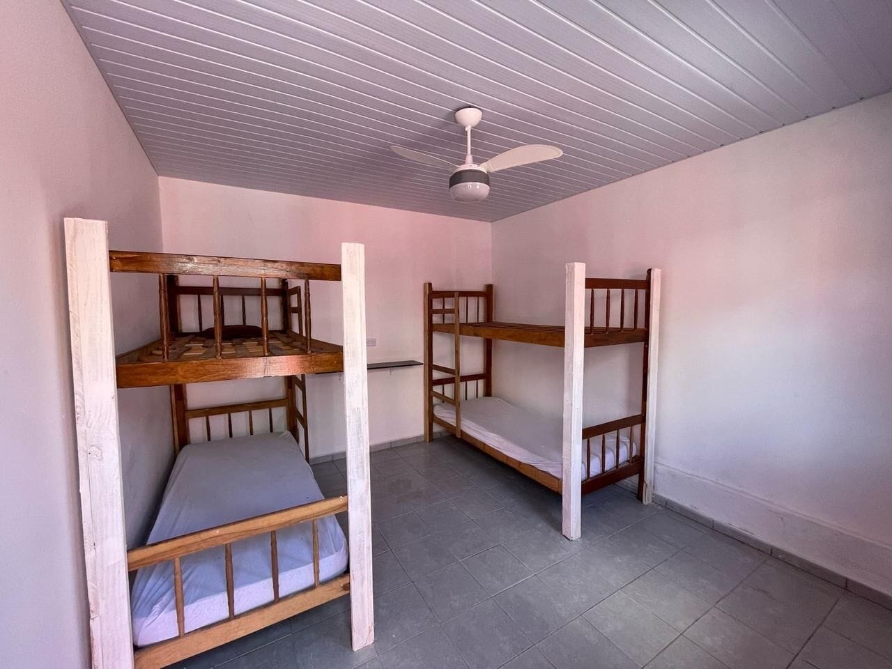 Una habitación con literas, ventilador de techo y piso de baldosas.