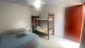 A room with bunk beds, a bed with a patterned bedspread, a ceiling fan, and a red door. - Villa Callegaro Hotel Capivari SP (Capivari)