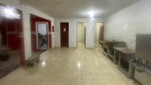 A hallway with a tiled floor, a red door, a white door, and a sink area with a mirror. - Villa Callegaro Hotel Capivari SP (Capivari)