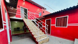 A red building with a staircase leading to an upper level, a door, and a window. - Villa Callegaro Hotel Capivari SP (Capivari)