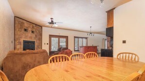 A dining room with a wooden table and chairs, a fireplace, and a stone wall.