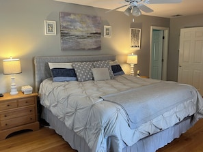 Un dormitorio con cama, mesitas de noche, ventilador de techo y decoración en la pared.