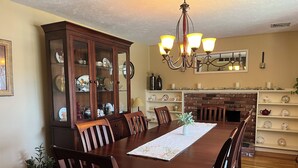 Un comedor con una mesa de madera, sillas, una aparadora y una chimenea.