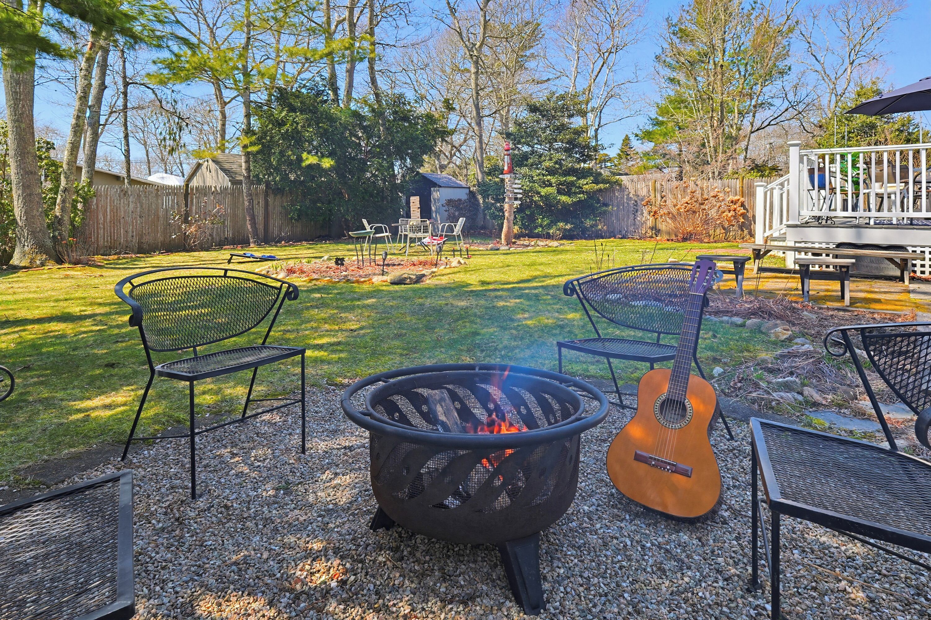 Ein Garten mit Feuerstelle, Gartenmöbeln und einer Gitarre.