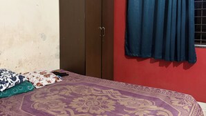 Une chambre à coucher avec un lit, une armoire, des rideaux et une horloge au mur.