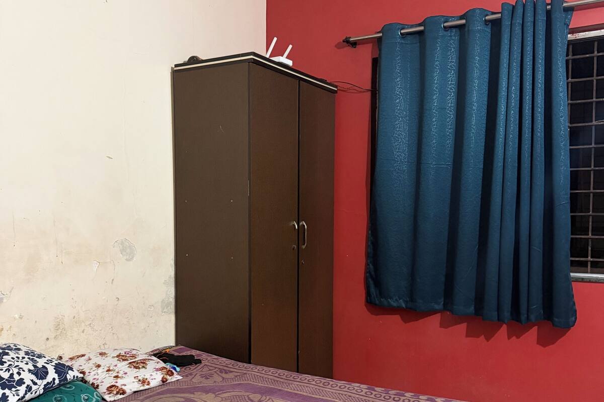 Una camera da letto con un letto, un armadio, tende e una sveglia appesa al muro.