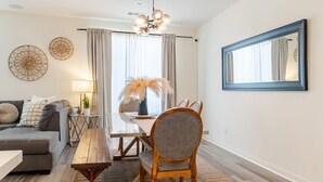 Ein Wohnzimmer mit Sofa, Esstisch, Stuhl, Lampe und Spiegel.