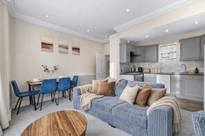 A modern living room with a sofa, chairs, and a dining table. - Stylish 2BR Kensington Retreat, 1 min to Station! (Greater London)