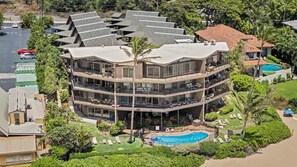 Ein mehrstöckiges Hotel mit Pool, umgeben von üppiger Vegetation und Palmen.
