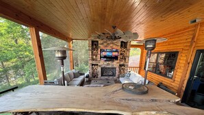 Un interior de madera con una mesa grande, sillas, chimenea y televisor.