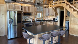 Una cocina moderna con una isla central, electrodomésticos de acero inoxidable y una pared decorada con piedra.