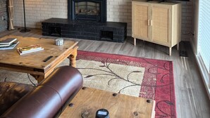 Ein Wohnzimmer mit Kamin, Fernseher, Sofa und Couchtisch.