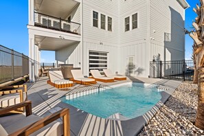 A two-story building with a swimming pool, outdoor seating, and a balcony.