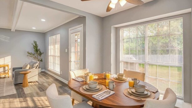 A dining area with a wooden table set for breakfast, large windows with blinds, and a ceiling fan. - Game Room & BBQ at Renovated Montgomery Retreat (Montgomery)