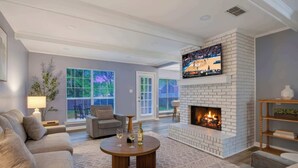 A living room with a fireplace, a television, and a sofa. - Game Room & BBQ at Renovated Montgomery Retreat (Montgomery)