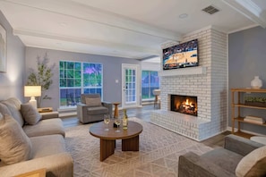 Una sala de estar con chimenea, televisor y sofá.