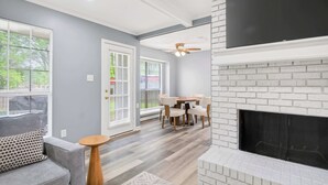 A living room with a fireplace, a dining area, and a sofa. - Game Room & BBQ at Renovated Montgomery Retreat (Montgomery)