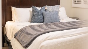 Ein Bett mit dunklem Kopfteil, weißen Kissen und einer grauen Decke.