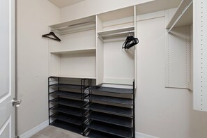 Um closet espaçoso com prateleiras abertas, uma estante de metal e uma porta.