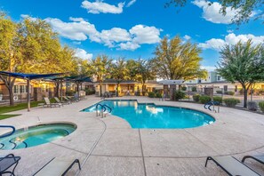 A swimming pool with a sunken hot tub, lounge chairs, and a covered patio area.