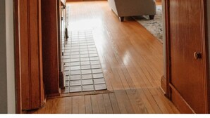 Un pasillo con puertas de madera, un radiador y un sofá al fondo.